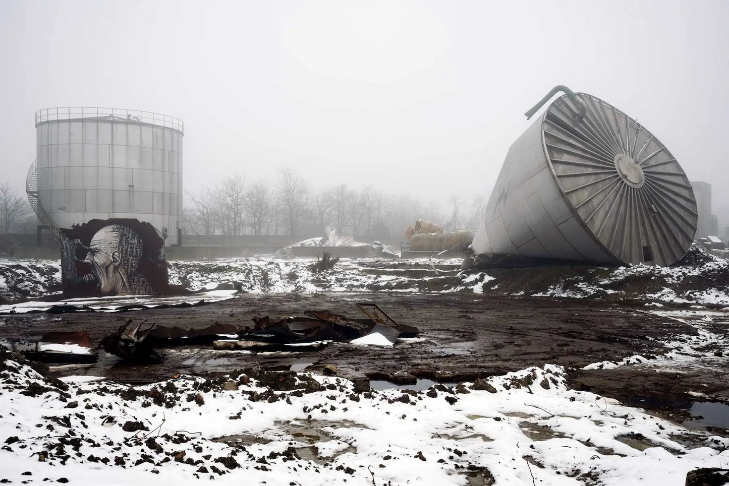 Nicola Bertellotti, La terra silenziosa, paesaggio industriale abbandonato con neve, silos e strutture metalliche